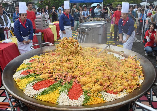 Japanese cooks in Tokyo make enough paella for 2,000 people in a pan two metres in diameter on July 5, 2014. Cooks at a Spanish restaurant used large amount of food including 80 kg of rice, 80 kg chicken, 30 kg kidney beans, 10 kg green peas, 10 litres of olive oil to make the large paella to promote Spanish dishes. (Photo by Toru Yamanaka/AFP Photo)