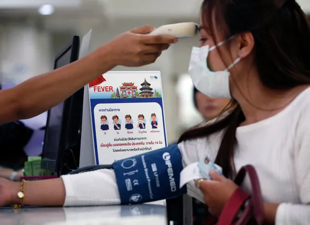 A nurse checks a patient's body temperature next to a campaign poster alerting on the coronavirus at a hospital in Bangkok, Thailand, 22 January 2020. The SARS-like coronavirus was detected in three Chinese tourists as well as a 73-year-old Thai woman who was infected after traveling to Wuhan, China. China confirmed 440 cases of Wuhan pneumonia with nine deaths, according to the National Health Commission on a press conference. The respiratory virus was first detected in Wuhan and can be passed between humans. So far it has spread to the USA, Thailand, South Korea, Japan and Taiwan. (Photo by Rungroj Yongrit/EPA/EFE)