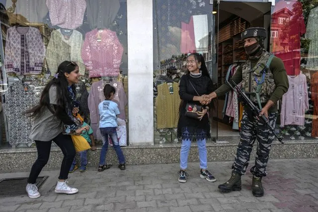 An Indian tourist girl shakes hand with a paramilitary soldier as he guards at a market in Srinagar, Indian controlled Kashmir, Thursday, June 2, 2022. (Photo by Mukhtar Khan/AP Photo)