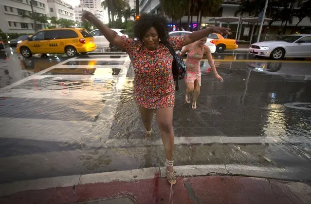 A woman jumps over a puddle as she crosses a street after a torrential downpour in the South Beach part of Miami, July 18, 2014. (Photo by Carlo Allegri/Reuters)