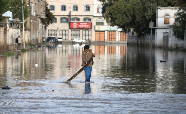 A boy plays on a flooded street following rains in Sanaa, Yemen on August 15, 2024. (Photo by Khaled Abdullah/Reuters)