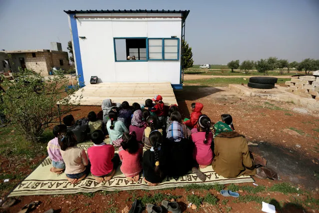 Children watch as volunteer teachers perform a puppet show inside a mobile educational caravan for children who do not have access to schools on the outskirts of the Syrian rebel-held town of Saraqib, Idlib province March 10, 2016. (Photo by Khalil Ashawi/Reuters)
