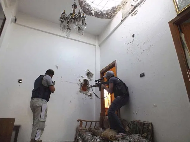 Two members of the Free Syrian Army hold their weapons as they take defense positions in a house in El Moalimin neighborhood in Homs July 14, 2012. The Red Cross now views fighting in Syria as an internal armed conflict – a civil war in layman's terms – crossing a threshold experts say can help lay the ground for future prosecutions for war crimes. The independent humanitarian agency had previously classed the violence in Syria as localised civil wars between government forces and armed opposition groups in three flashpoints – Homs, Hama and Idlib. (Photo by Yazen Homsy/Reuters)