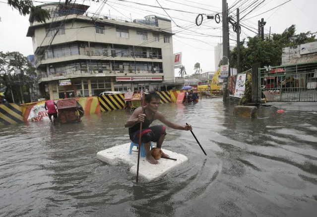 A man uses sticks to move a styrofoam block he is riding along a flooded road in suburban Mandaluyong, east of Manila, Philippines, as monsoon downpours intensify while Typhoon Nepartak exits the country on Friday, July 8, 2016. In the Philippine capital, Manila, and outlying provinces, classes in many schools were suspended and at least six flights, including one scheduled to come from Taiwan, were canceled because of stormy weather and floods following monsoon downpours intensified by the typhoon, Filipino officials said. (Photo by Aaron Favila/AP Photo)