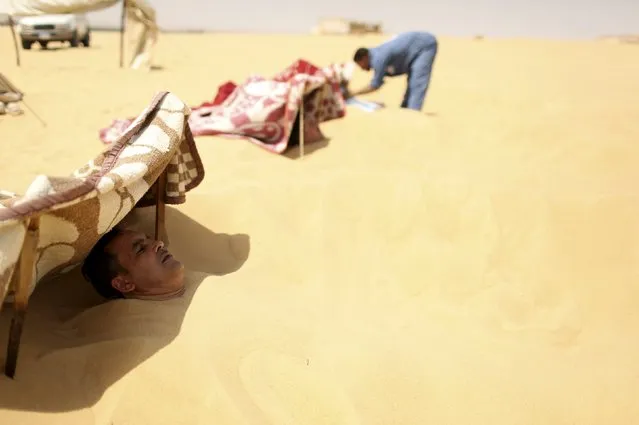A woker tends to patients buried in the sand in Siwa, Egypt, August 11, 2015. (Photo by Asmaa Waguih/Reuters)