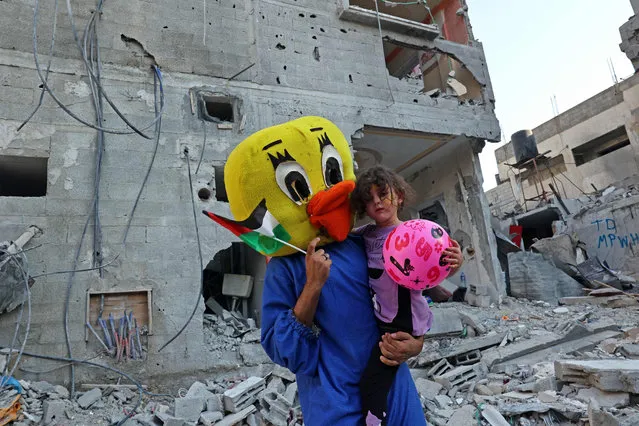 A Palestinian clown carries a child during a show amidst the rubble of a building destroyed in the latest round of fighting between Israel and Palestinian militants, in Rafah in the southern Gaza Strip on August 9, 2022. An Egypt-brokered ceasefire reached late on August 7 ended the intense fighting that killed 46 people including 16 children and wounded 360 in the enclave, according to Gaza's health ministry, updating an earlier toll of 44. (Photo by Said Khatib/AFP Photo)