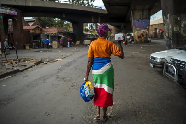 A woman living near the traditional medicine market walks away with donated food baskets following a distribution by private donors Monday, April 13, 2020 downtown Johannesburg. Because of South Africa's imposed lockdown to contain the spread of COVID-19, many are not able to work. (Photo by Jerome Delay/AP Photo)
