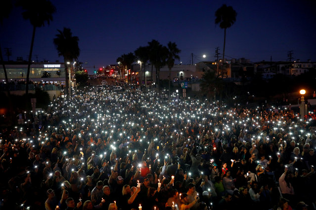 People hold candles and flashlights into the air during a memorial for Rachael Parker and Sandy Casey, Manhattan Beach city employees and victims of the October 1st Las Vegas Route 91 music festival mass shooting, in Manhattan Beach, California, U.S., October 4, 2017. (Photo by Patrick T. Fallon/Reuters)