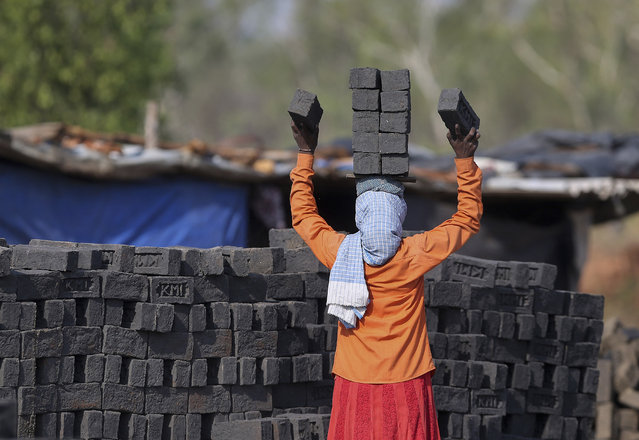 An Indian woman stacks bricks on her head to carry as she works at a brick kiln on the outskirts of Hyderabad, India, Thursday, April 30, 2020. India says it has achieved tremendous gains and improvement in curbing the coronavirus infections through a stringent lockdown imposed across the country five weeks ago. The government recently allowed reopening of neighborhood shops in cities and towns and resumption of manufacturing and farming activity in rural India to help millions of poor people who lost work. (Photo by Mahesh Kumar A./AP Photo)