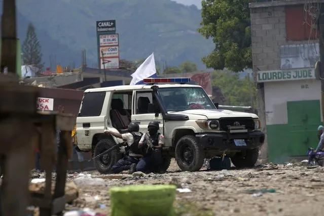 Police officers take cover as protesters throw rocks at them during a protest to demand that Haitian Prime Minister Ariel Henry step down and a call for a better quality of life in Port-au-Prince, Haiti, Wednesday, September 7, 2022. (Photo by Odelyn Joseph/AP Photo)