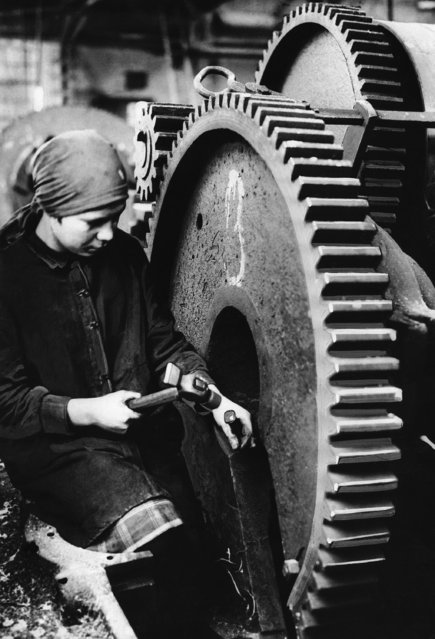 In present day proletarian Russia everybody must work, even women and girls whether it be in field, factory or forge. The picture shows a young Leningrad female worker remaining out a huge cog wheel which is to form part of a tractor plant in the old capital shown on May 21, 1934. (Photo by AP Photo)