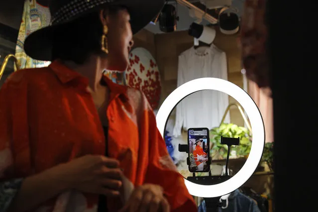 In this April 27, 2020, photo, Song Huiyan shows her fashion dresses for her online clients during the live-streaming at her clothing shop in Beijing. Retailers in China are embracing livestreaming as a sales channel amid a Chinese “shoppertainment” boom accelerated during the COVID-19 pandemic. Via livestreaming, retailers can interact with customers in real time, while customers make purchases directly in the stream. (Photo by Andy Wong/AP Photo)