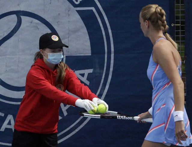 A ball girl wearing a face mask hands over balls to Petra Kvitova during her Czech Tennis President's Cup charity tournament match against Barbora Krejcikova in Prague, Czech Republic, Tuesday, May 26, 2020. The sporting event can take place as the Czech government is taking further steps to ease its restrictive measures adopted to contain the coronavirus pandemic. (Photo by Petr David Josek/AP Photo)