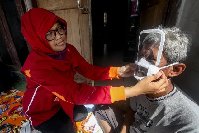 Deaf woman Dwi Rahayu (L) puts a transparent face mask on her husband Elfiandi in Yogyakarta, Indonesia, 13 May 2020. Amid the coronavirus pandemic, Dwi Rahayu and her husband Elfiandi have turned to producing transparent face masks to help fellow deaf people read lips. They sell the masks for 20,000 Rupiah (around 1.20 Euro) each. (Photo by Boy Triharjanto/EPA/EFE/Rex Features/Shutterstock)