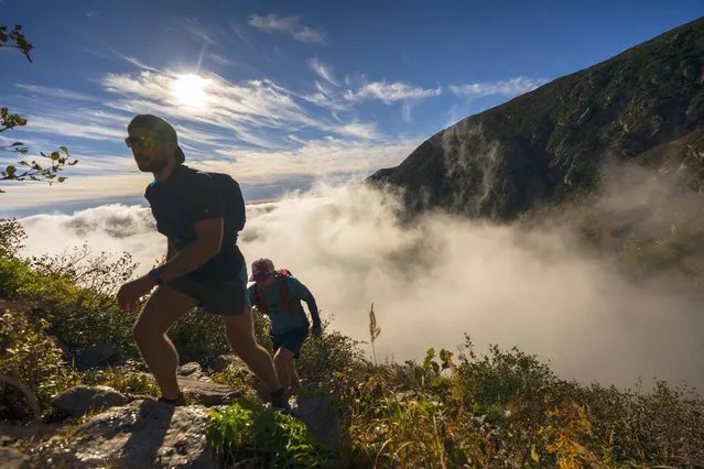 Hikers climb out of the clouds on their way to the summit of 6,288-foot Mount Washington, N.H., Sunday, October 2, 2022. A high pressure system allowed outdoors enthusiasts throughout New England to enjoy pleasant weather during the first weekend of October. (Photo by Robert F. Bukaty/AP Photo)