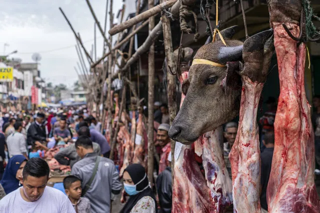 A buffalo's head hangs on a butcher's stall during “Meugang”, a local tradition where people shop for meat one day prior to the Eid al Fitr to be cooked and served during the holiday that marks the end of the holy fasting month of Ramadan, amid concerns of the new coronavirus outbreak, at Geudong market in North Aceh, Indonesia, Saturday, May 23, 2020. Indonesia has seen a surge in coronavirus infections ahead of this Sunday's celebrations marking the end of Ramadan, raising questions about the commitment to the virus fight from both the government and the public. (Photo by Zik Maulana/AP Photo)