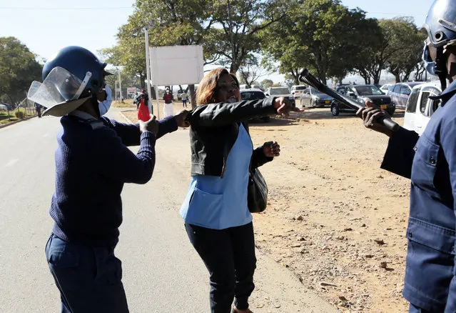 Riot police arrest a nurse who was protesting at a government hospital in Harare, Monday, July, 6, 2020. Thousands of nurses working in public hospitals stopped reporting for work in mid-June, part of frequent work stoppages by health workers who earn less than $50 a month and allege they are forced to work without adequate protective equipment. On Monday, dozens of nurses wearing masks and their white and blue uniforms gathered for protests at some of the country’s biggest hospitals in the capital, Harare, and the second-largest city of Bulawayo. (Photo by Tsvangirayi Mukwazhi/AP Photo)