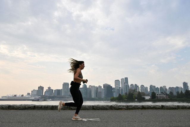 A woman runs along the seawall as an air quality warning for Vancouver has been extended as wildfires contribute to poor air quality, in Vancouver, British Columbia, Canada on September 12, 2022. (Photo by Jennifer Gauthier/Reuters)