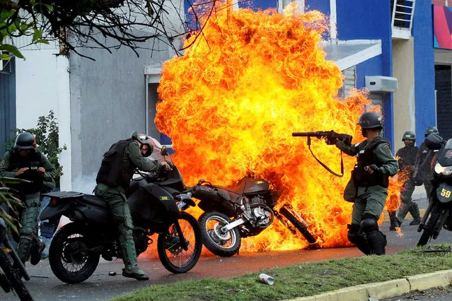 Riot security forces clash with demonstrators as a motorcycle is set on fire during a protest against Venezuelan President Nicolas Maduro's government in San Cristobal, Venezuela, May 29, 2017. Carlos Eduardo Ramirez: “Security forces arrived to disperse demonstrators that already had burned two taxis and a bus, throwing tear gas and pellets and the demonstrators' response was to throw molotov cocktails and one of those petrol bombs reached a National Guard member, setting him and the motorbike on fire”. (Photo by Carlos Garcia Rawlins/Reuters)