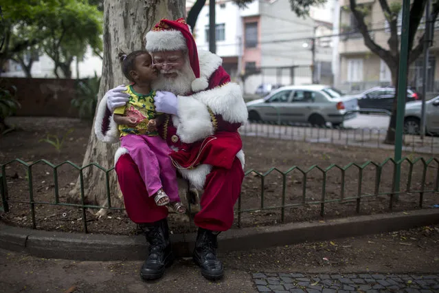 A professional Santa Claus poses for pictures with a girl during a reunion to celebrate the end of the Christmas season in Rio de Janeiro, Brazil, on December 26, 2017. The celebration, held every year the day after Christmas, is organized by the Brazil School of Santa Claus, which was founded in 1993. (Photo by Mauro Pimentel/AFP Photo)