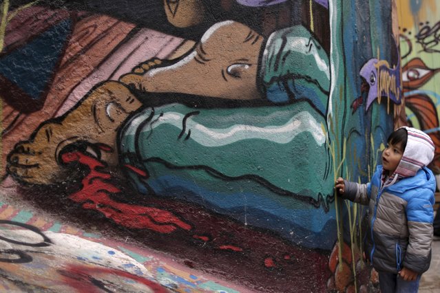 A child looks at a graffiti on a street in Valparaiso, Chile, June 27, 2015. (Photo by Ueslei Marcelino/Reuters)