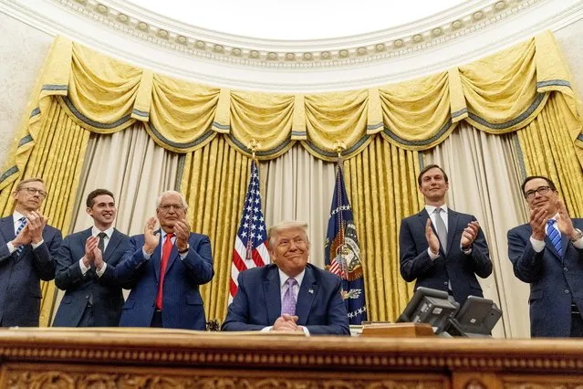 President Donald Trump, accompanied by From left, U.S. special envoy for Iran Brian Hook, Avraham Berkowitz, Assistant to the President and Special Representative for International Negotiations, U.S. Ambassador to Israel David Friedman, President Donald Trump's White House senior adviser Jared Kushner, and Treasury Secretary Steven Mnuchin, smiles in the Oval Office at the White House, Wednesday, August 12, 2020, in Washington. Trump said on Thursday that the United Arab Emirates and Israel have agreed to establish full diplomatic ties as part of a deal to halt the annexation of occupied land sought by the Palestinians for their future state. (Photo by Andrew Harnik/AP Photo)