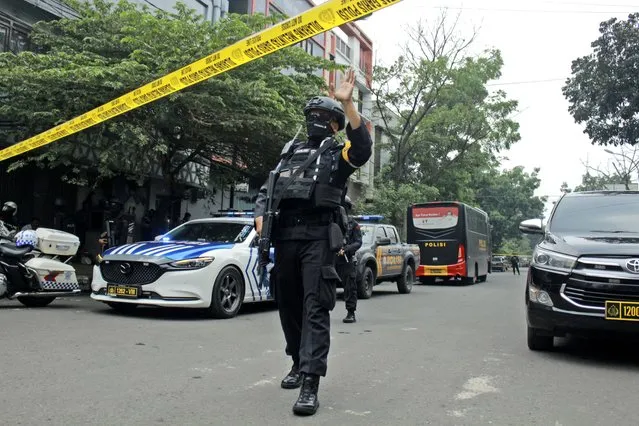 A police officer gestures at the crowd to move back as he guards a road leading to a police station where a bomb exploded in Bandung, West Java, Indonesia, Wednesday, December 7, 2022. A man blew himself up Wednesday at a police station on Indonesia's main island of Java in what appeared to be the latest in a string of suicide attacks in the world's most populous Muslim nation. (Photo by Kholid Parmawinata/AP Photo)