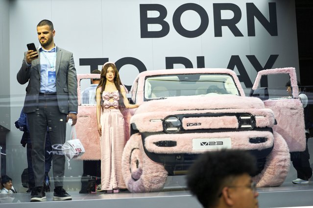 A woman stands next to a iCar 23 decked out with pink fur at the Shanghai auto show on Wednesday, April 23, 2025. (Photo by Ng Han Guan/AP Photo)
