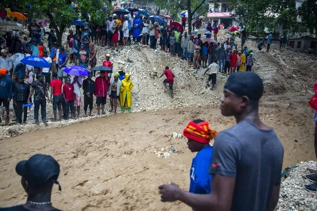 Locals stand on the banks of the Tet Dlo river during the passing of Tropical Storm Laura in Port-au-Prince, Haiti, Sunday, August 23, 2020. Tropical Storm Laura battered the Dominican Republic and Haiti and is heading for a possible hit on the Louisiana coast as a hurricane, along with Tropical Storm Marco. (Photo by Dieu Nalio Chery/AP Photo)