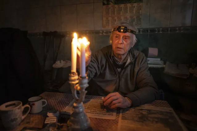 Volodymyr Dubrovsliy, a disabled pensioner, lights candles in his house after living without electricity for more than four months in Kupiansk, Kharkiv region, Ukraine, Wednesday, December 28, 2022. (Photo by Evgeniy Maloletka/AP Photo)