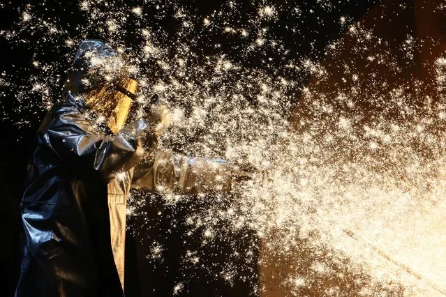 A steel worker of ThyssenKrupp stands amid sparks of raw iron coming from a blast furnace at a ThyssenKrupp steel factory in Duisburg, western Germany on November 14, 2022. (Photo by Wolfgang Rattay/Reuters)