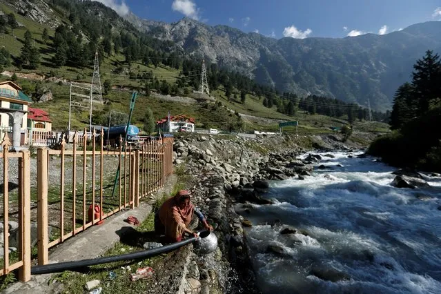 A woman fills her container using a water pipe alongside a stream at Gagangeer in Kashmir's Ganderbal district on September 3, 2020. (Photo by Danish Ismail/Reuters)