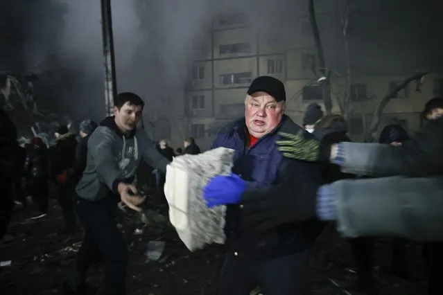 Local residents clear the rubble after a Russian rocket hit a multistory building leaving many people under debris in Dnipro, Ukraine, Saturday, January 14, 2023. (Photo by Roman Chop/AP Photo)