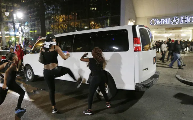 Demonstrators protest Tuesday's fatal police shooting of Keith Lamont Scott in Charlotte, N.C. on Wednesday, September 21, 2016. Protesters rushed police in riot gear at a downtown Charlotte hotel and officers have fired tear gas to disperse the crowd. At least one person was injured in the confrontation, though it wasn't immediately clear how. Firefighters rushed in to pull the man to a waiting ambulance. (Photo by Chuck Burton/AP Photo)