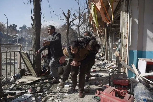 Afghan volunteers carry a body at the scene of a car bomb exploded in front of the old Ministry of Interior building in Kabul on January 27, 2018. An ambulance packed with explosives blew up in a crowded area of Kabul on January 27, killing at least 17 people and wounding 110 others, officials said, in an attack claimed by the Taliban. (Photo by Wakil Kohsar/AFP Photo)