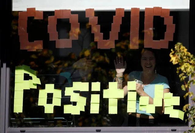 People wave through the window of a student accommodation building with a “Covid Positive” sign displayed in it, following the outbreak of the coronavirus disease (COVID-19 in Manchester, Britain, September 27, 2020. (Photo by Phil Noble/Reuters)