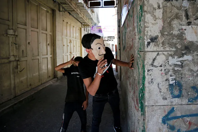 A Palestinian demonstrator looks towards Israeli troops during a protest, in Hebron in the Israeli-occupied West Bank on September 25, 2020. (Photo by Mussa Qawasma/Reuters)