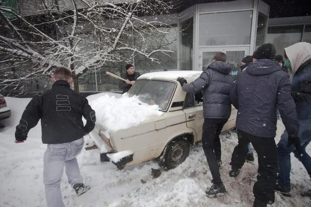 In this photo taken on Friday, March 15, 2013, members of a pro-Kremlin youth group attack pushers of spice, a synthetic drug, one of which is swinging a bat at them in Moscow, Russia. Russian officials and anti-drugs campaigners say that spice has become one of the most dangerous drugs widely available to youngsters and almost impossible to ban because of the constantly changing chemical ingredients. (Photo by Alexander Zemlianichenko Jr/AP Photo)