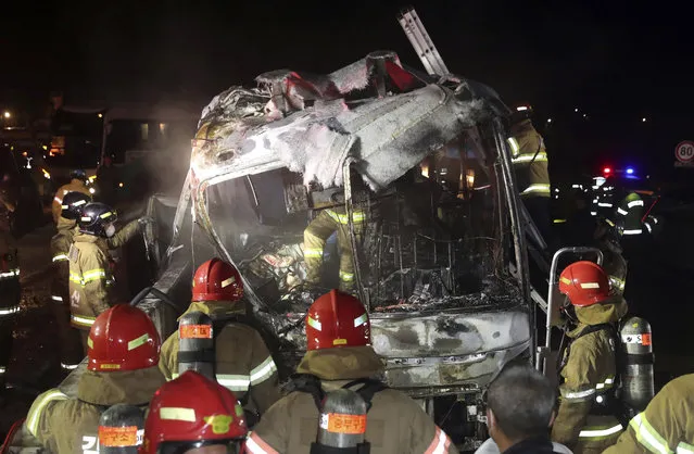 South Korean firefighters check a burned out bus on the Gyeongbu Expressway near the southeastern city of Ulsan, South Korea, Friday, October 14, 2016. Twenty people, including the driver, were on the bus when it smashed into the guardrail and caught fire on the expressway, officials said. (Photo by Kim Yong-tae/Yonhap via AP Photo)