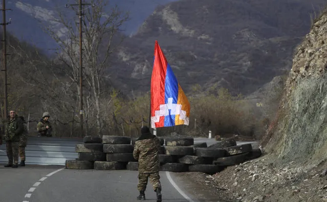 An ethnic Armenian soldier walks with Nagorno-Karabakh's flag towards a checkpoint near village of Charektar in the separatist region of Nagorno-Karabakh at a new border with Kalbajar district turned over to Azerbaijan, Wednesday, November 25, 2020. The Azerbaijani army has entered the Kalbajar region, one more territory ceded by Armenian forces in a truce that ended deadly fighting over the separatist territory of Nagorno-Karabakh, Azerbaijan's Defense Ministry said Wednesday. The cease-fire, brokered by Russia two weeks ago, stipulated that Armenia hand over control to Azerbaijan of some areas its holds outside Nagorno-Karabakh's borders. (Photo by Sergei Grits/AP Photo)