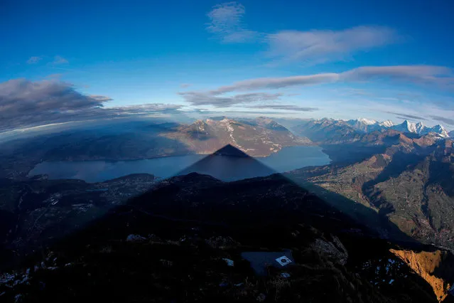 A picture taken on November 12, 2020 shows the 2,362 meters high mountain Niesen casting its near-perfect pyramid shape shadow during sunset across Lake Thun near Spiez in the Berner Alps. The weather phenomenon that has inspired many artist to depict it happens during clear weather conditions form mid November till the 20th of January and reaches its peak on December 21st. (Photo by Stefan Wermuth/AFP Photo)