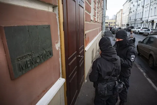 Two Russian police officers stand in front the door of the Memorial office in Moscow, Russia, Tuesday, March 21, 2023. The Russian authorities on Tuesday raided homes and offices of multiple human rights advocates and historians with the prominent rights group Memorial that won the Nobel Peace Prize last year. (Photo by AP Photo/Stringer)