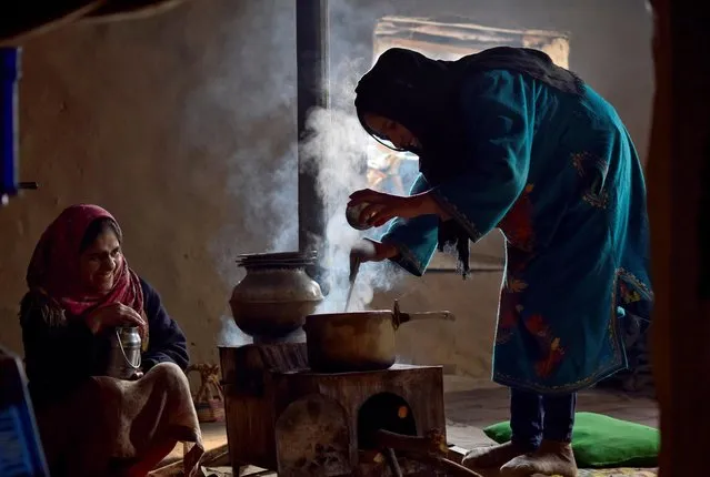 Women belonging to Kashmiri Gujjar community cook food on a wood burner inside a mud house at Mulnar on the outskirts of Srinagar on December 31, 2020. (Photo by Sanna Irshad Mattoo/Reuters)