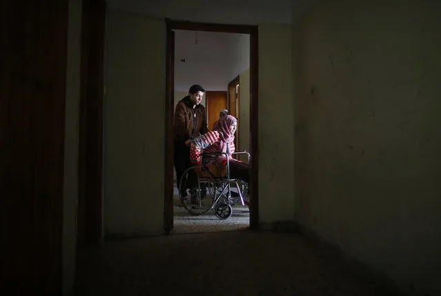 A brother of 15-year-old Palestinian girl Manar Al-Shinbari pushes her in a wheelchair inside an apartment in Jabaliya refugee camp in the northern Gaza Strip January 13, 2015. (Photo by Mohammed Salem/Reuters)