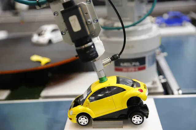 A robotic arm by Mitsubishi Electric assembles a toy car at the System Control Fair SCF 2015 in Tokyo, Japan December 2, 2015. (Photo by Thomas Peter/Reuters)