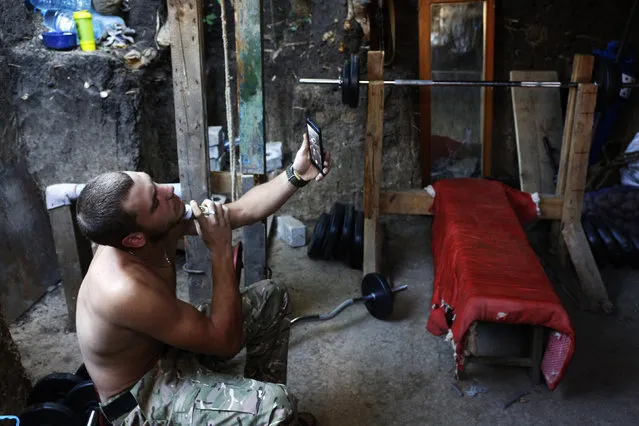 A Ukrainian serviceman looks at his image on his mobile phone camera as he shaves in an improvised sports hall on the front-line with Russia-backed separatists near the southeastern city of Mariupol on June 12, 2018. Germany and France voiced cautious optimism Monday that Russia and Ukraine will take steps to revive the long-stalled peace process in the smouldering Ukraine war that has claimed 10,000 lives. Despite high tensions between Western powers and President Vladimir Putin's Russia, the four foreign ministers held their first meeting since early last year to revitalise a long ignored truce agreement. (Photo by Anatolii Stepanov/AFP Photo)