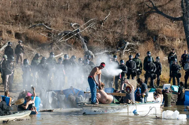 Police use pepper spray against people standing in the water of a river during a protest against the building of a pipeline near the Standing Rock Indian Reservation near Cannonball, North Dakota, U.S. November 2, 2016. (Photo by Stephanie Keith/Reuters)