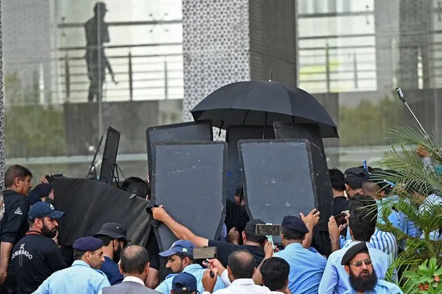 Security personnel with ballistic shields escort former Pakistan's prime minister Imran Khan, at the High Court in Islamabad on June 8, 2023. (Photo by Farooq Naeem/AFP Photo)