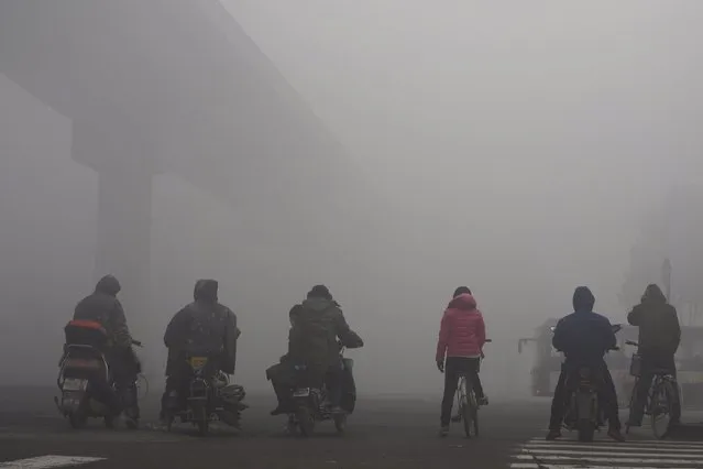 Residents on their bicycles and electric bikes wait for the traffic at an intersection amid heavy smog in Shijiazhuang, Hebei province, China, December 10, 2015. (Photo by Reuters/Stringer)