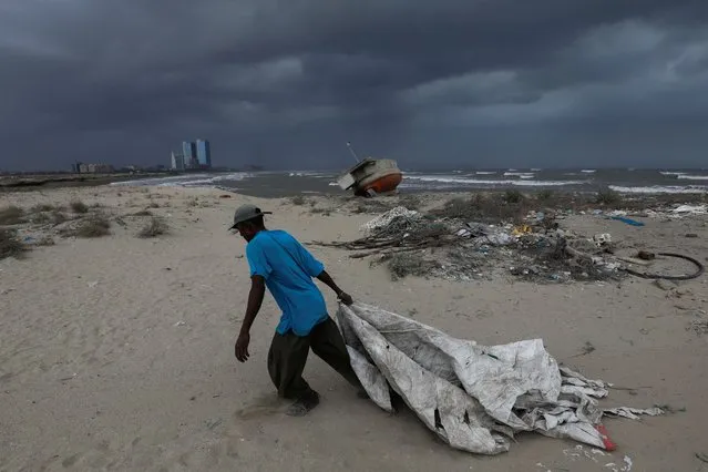Sooraj, 32, a fisherman and diver, pulls a sheet to cover his belongings, with rain clouds in the background, before the arrival of cyclonic storm, Biparjoy, over the Arabian Sea, in Karachi, Pakistan on June 15, 2023. (Photo by Akhtar Soomro/Reuters)